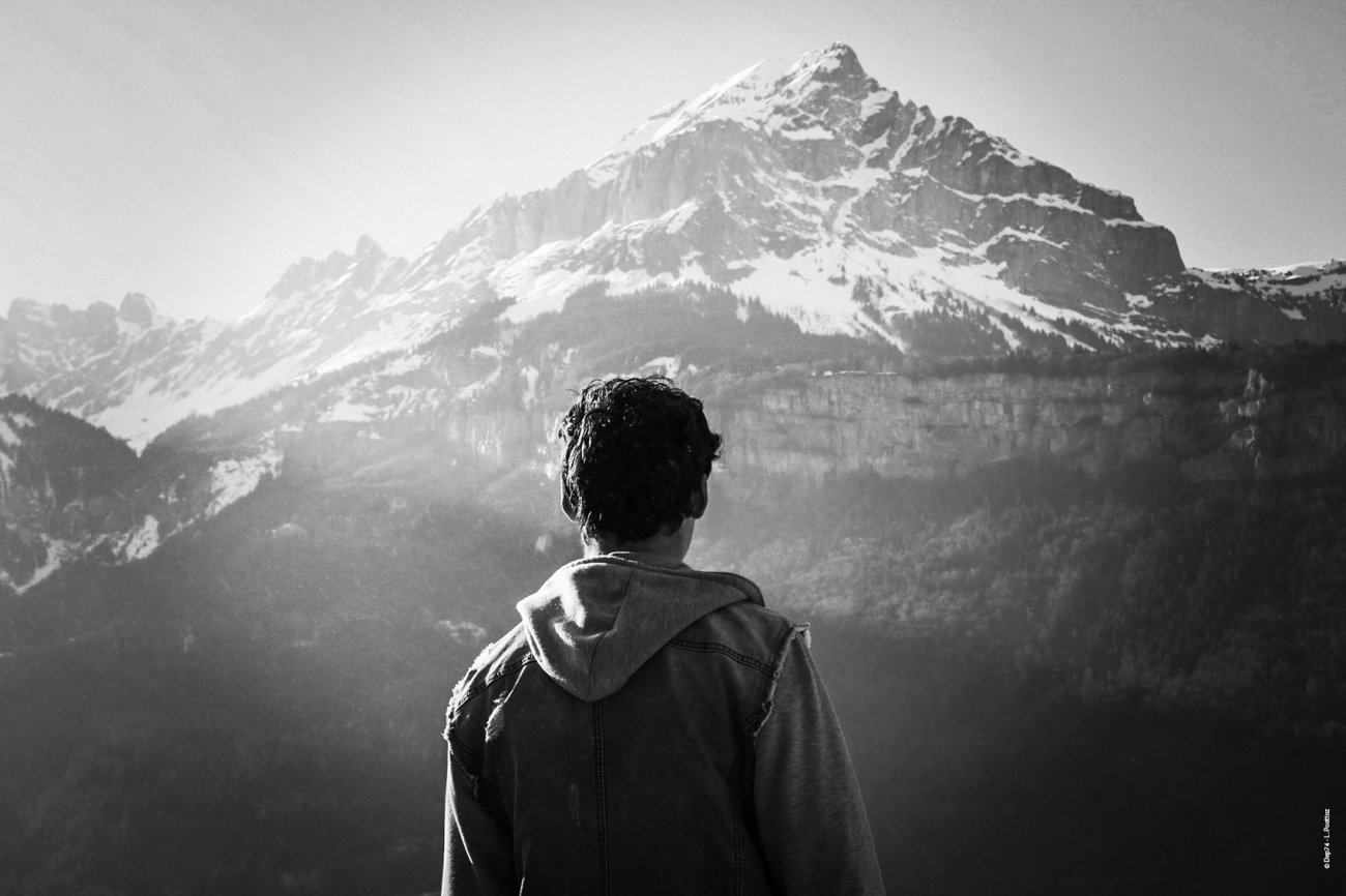 Jeune homme de dos regardant un paysage de montagne. 