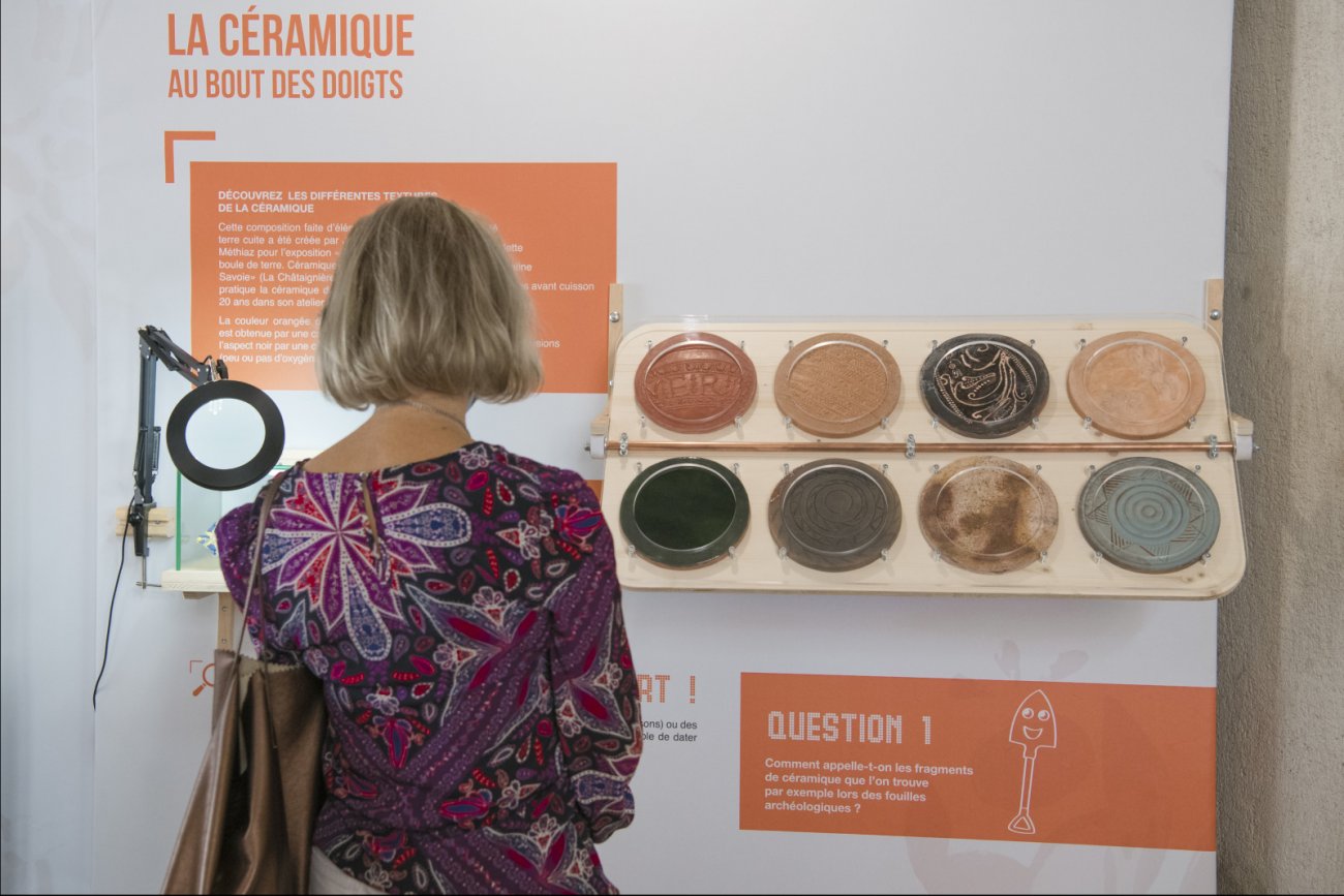 Une femme regarde des céramiques retrouvées à la chartreuse de Mélan.