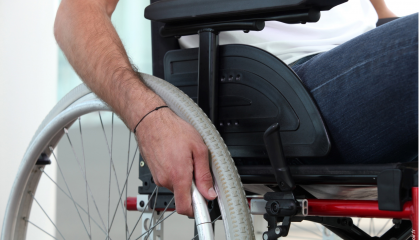 Handicap moteur : gros plan sur une main posée sur la roue d'un fauteuil roulant